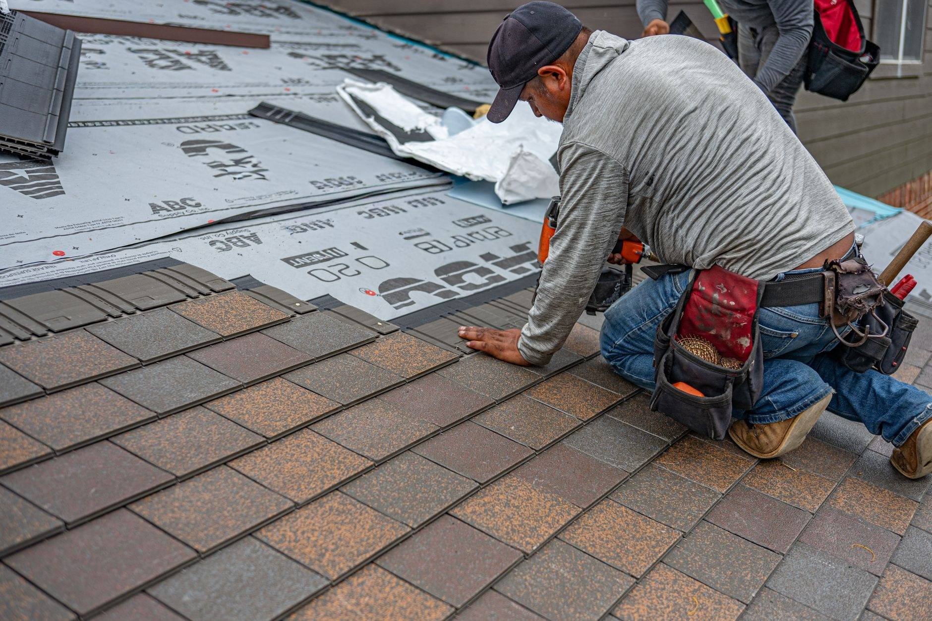 Two Johannemann and Sons roofers working on a slate roof between two chimneys