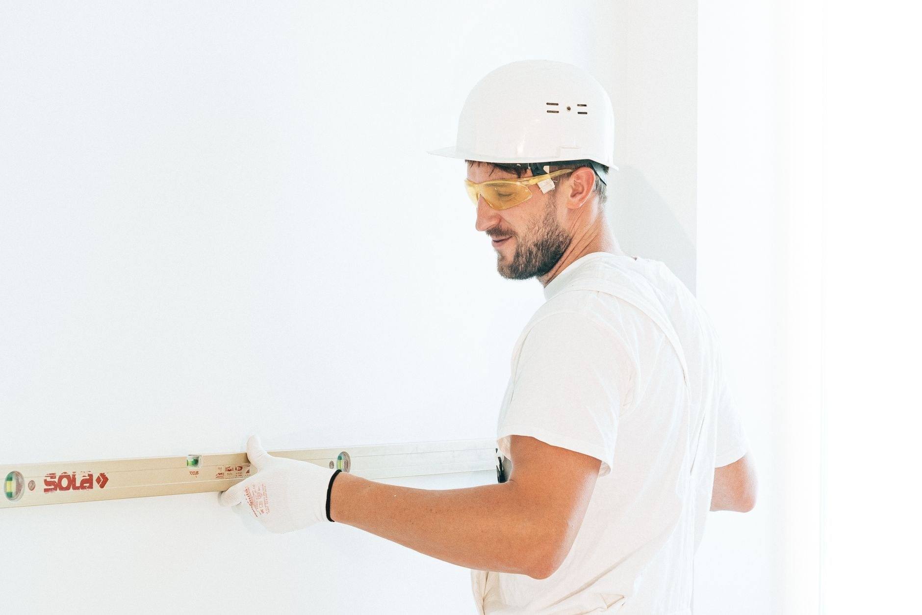 Gloved hands measuring a piece of timber with a tape measure