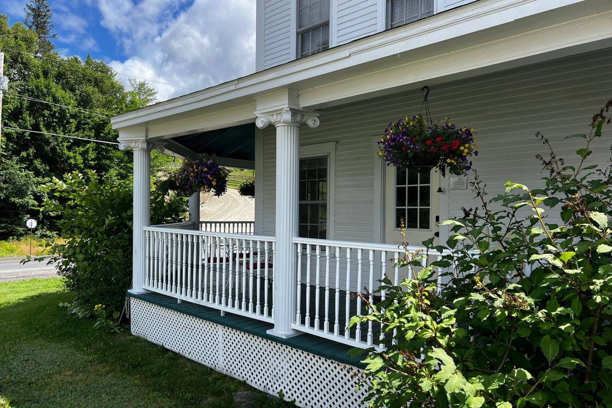 A covered front porch with white columns and railings