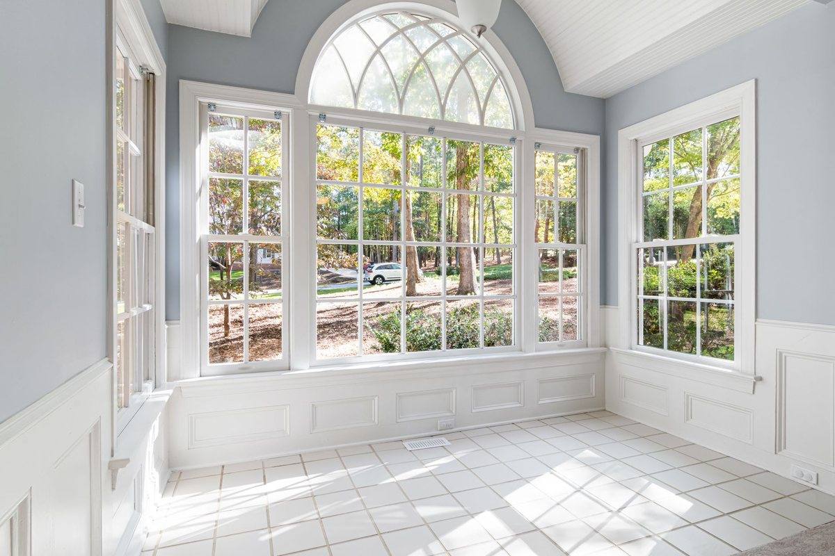 A sunroom with arched windows and daylight across the floor