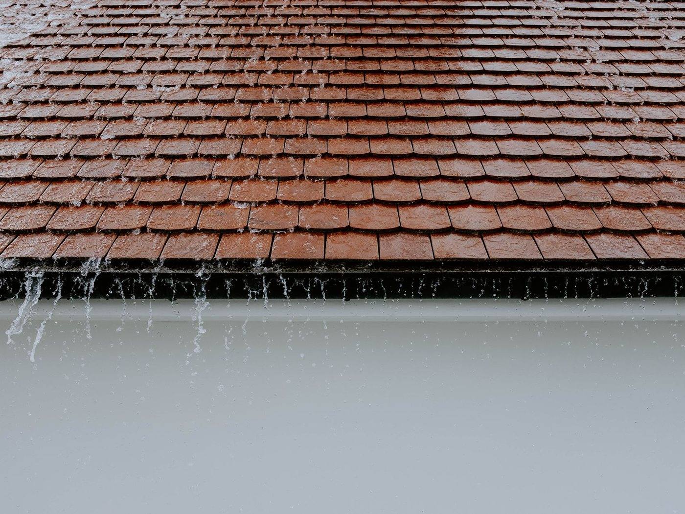 Rain sheeting off a tiled roof edge into a gutter
