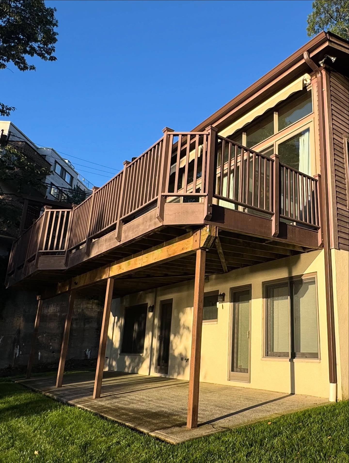 The rear of the Edgewater house before: dark brown siding and a weathered brown timber deck