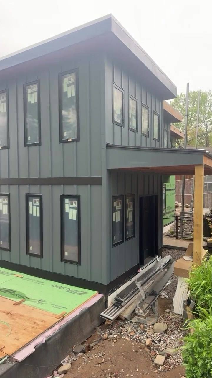 A custom home we are building in Edgewater, clad in dark blue-gray board-and-batten siding with black-trimmed windows