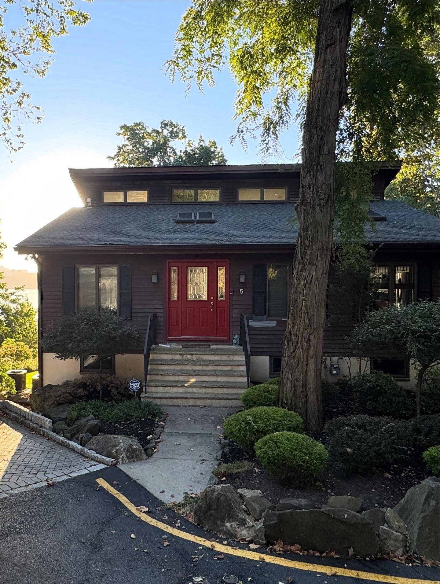 The front of the Edgewater house before the work: dark brown siding and a red front door
