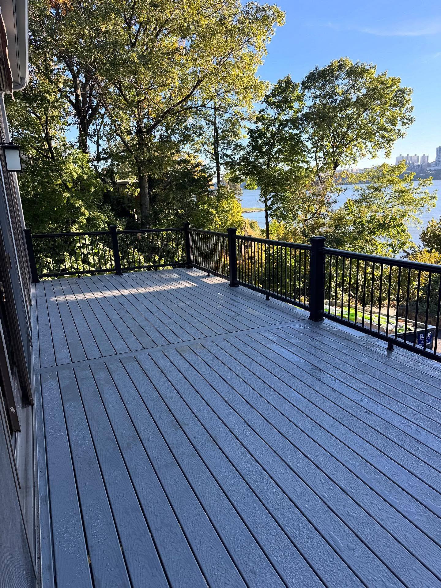 The rebuilt Trex deck on the Edgewater house, gray boards and black rails, with the Hudson through the trees