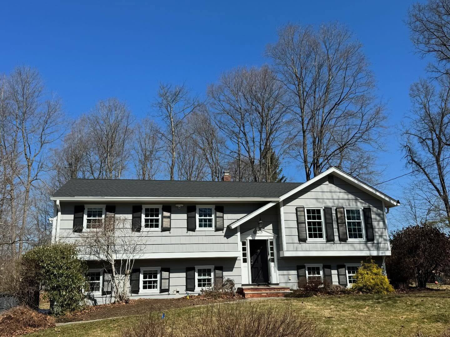 A split-level home in Franklin Lakes with a new GAF Charcoal shingle roof under a clear sky