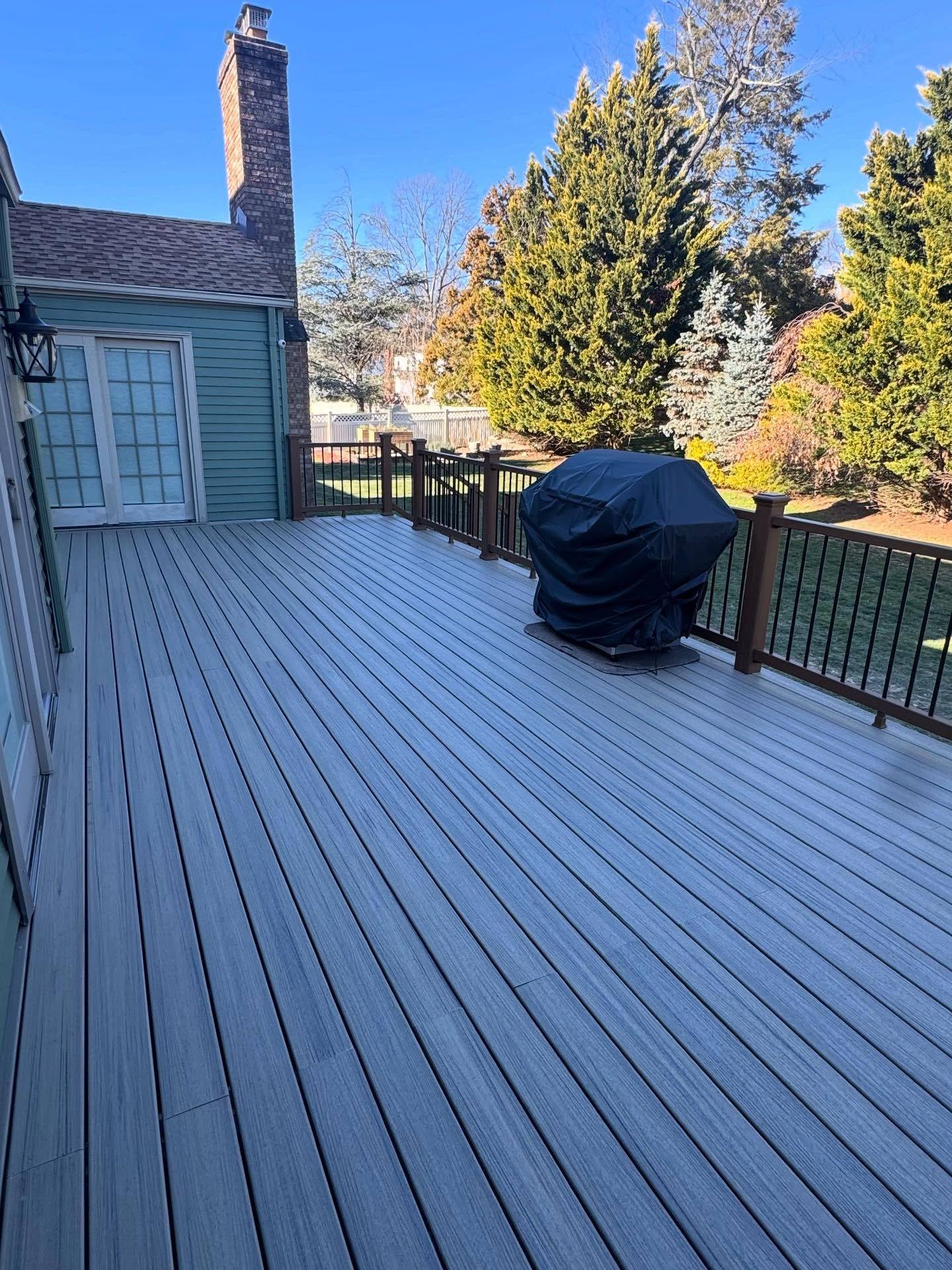 The finished Trex deck surface on the Oradell house, gray boards running to a rail of black balusters