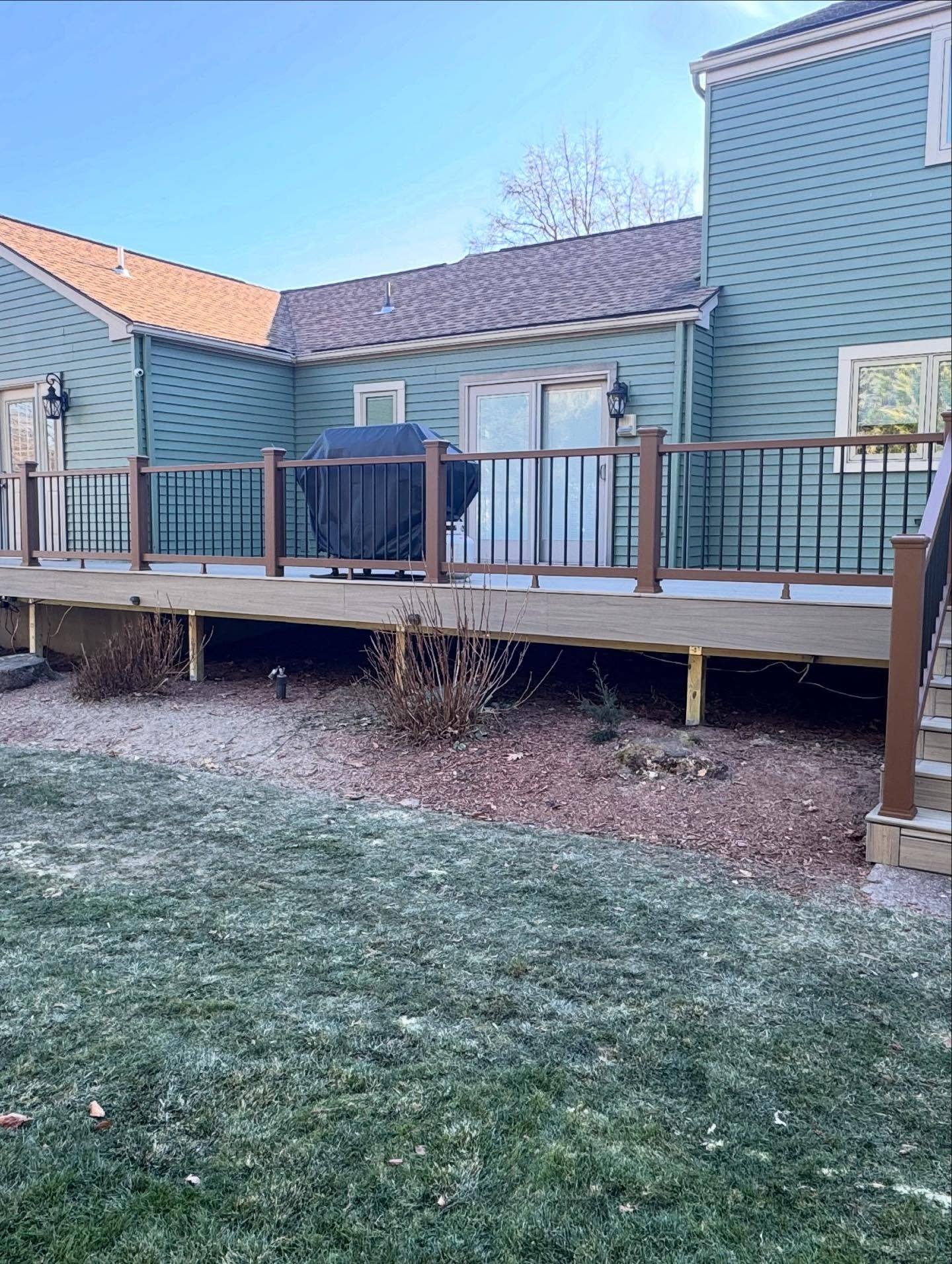 The finished Trex deck on the Oradell house, seen from the yard, with its rail of black balusters and new stairs