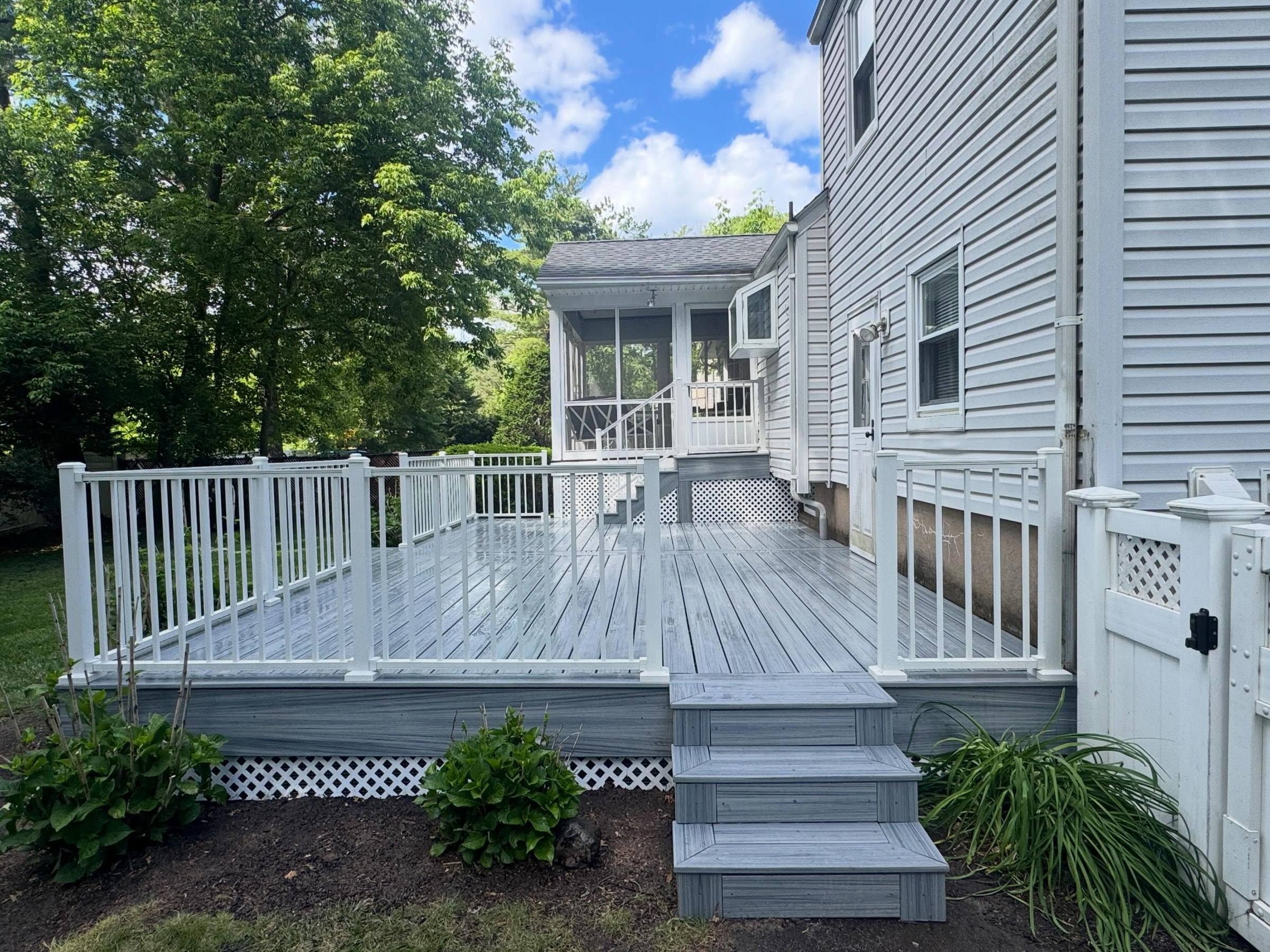 The finished four-day deck in light gray composite with white railings