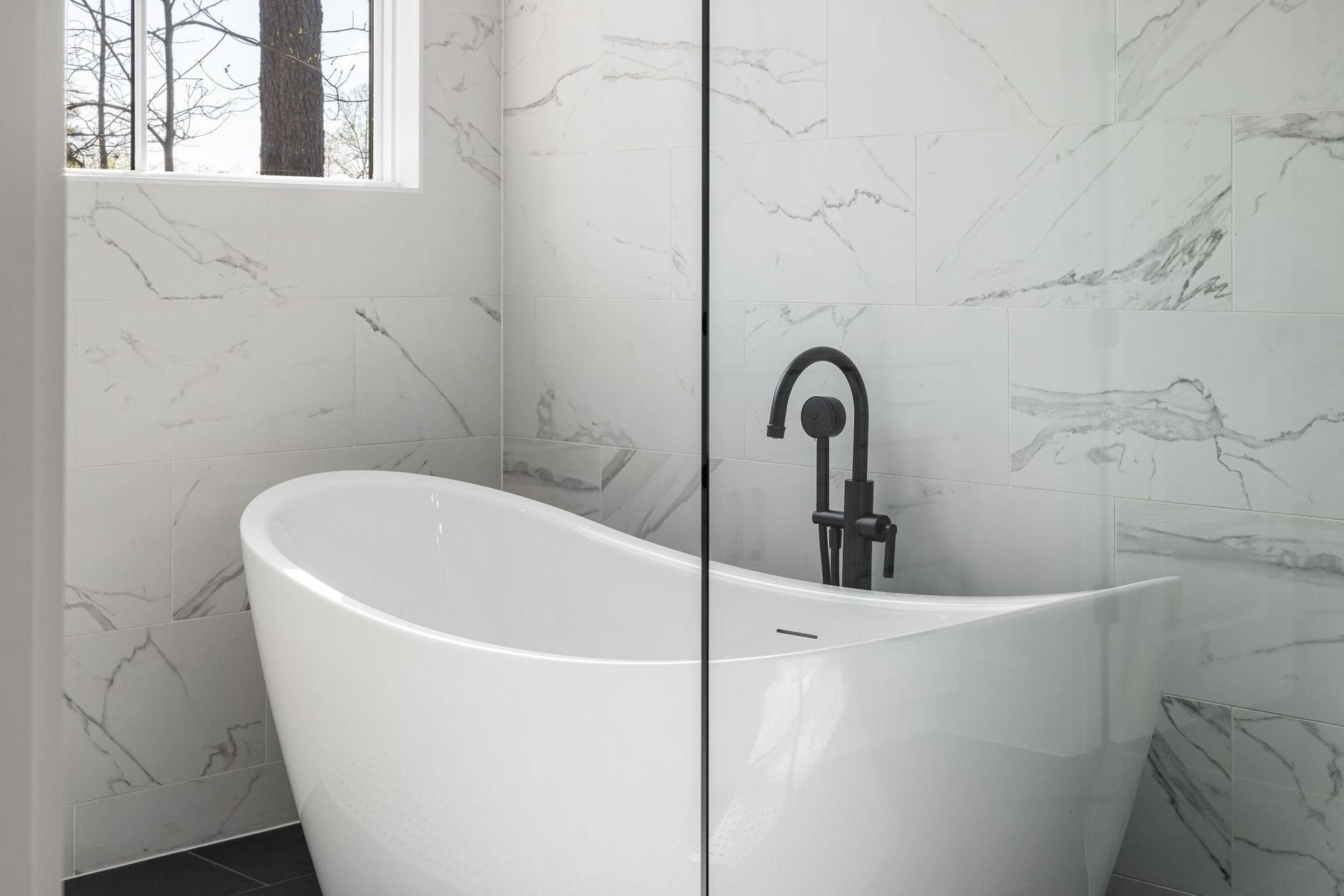 A marble bathroom with a freestanding tub and wood vanity