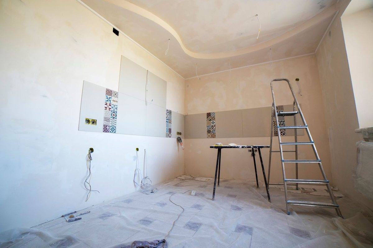 A room stripped back for renovation with a ladder and dust sheets