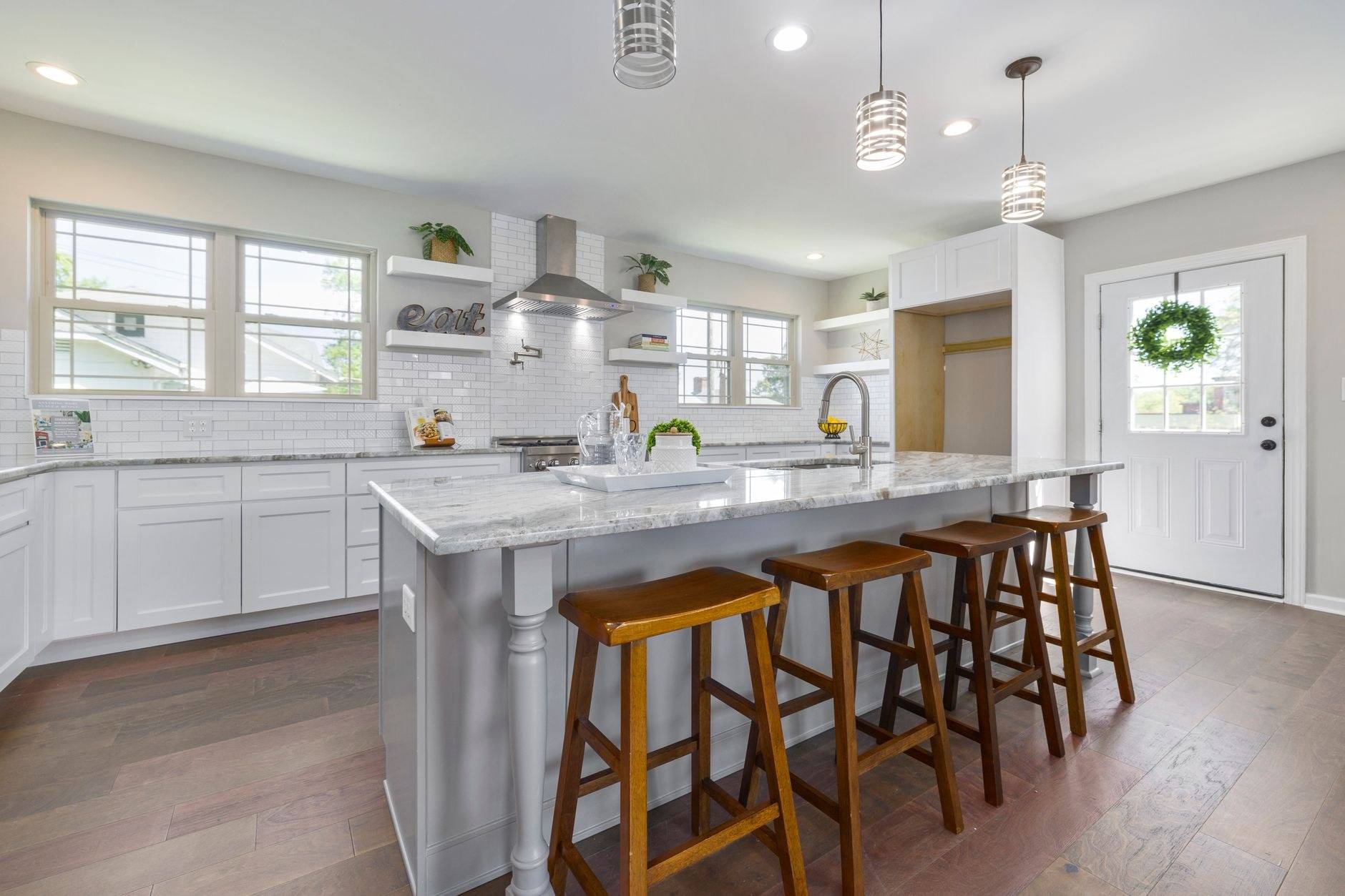 A renovated kitchen with a marble island and pendant lighting