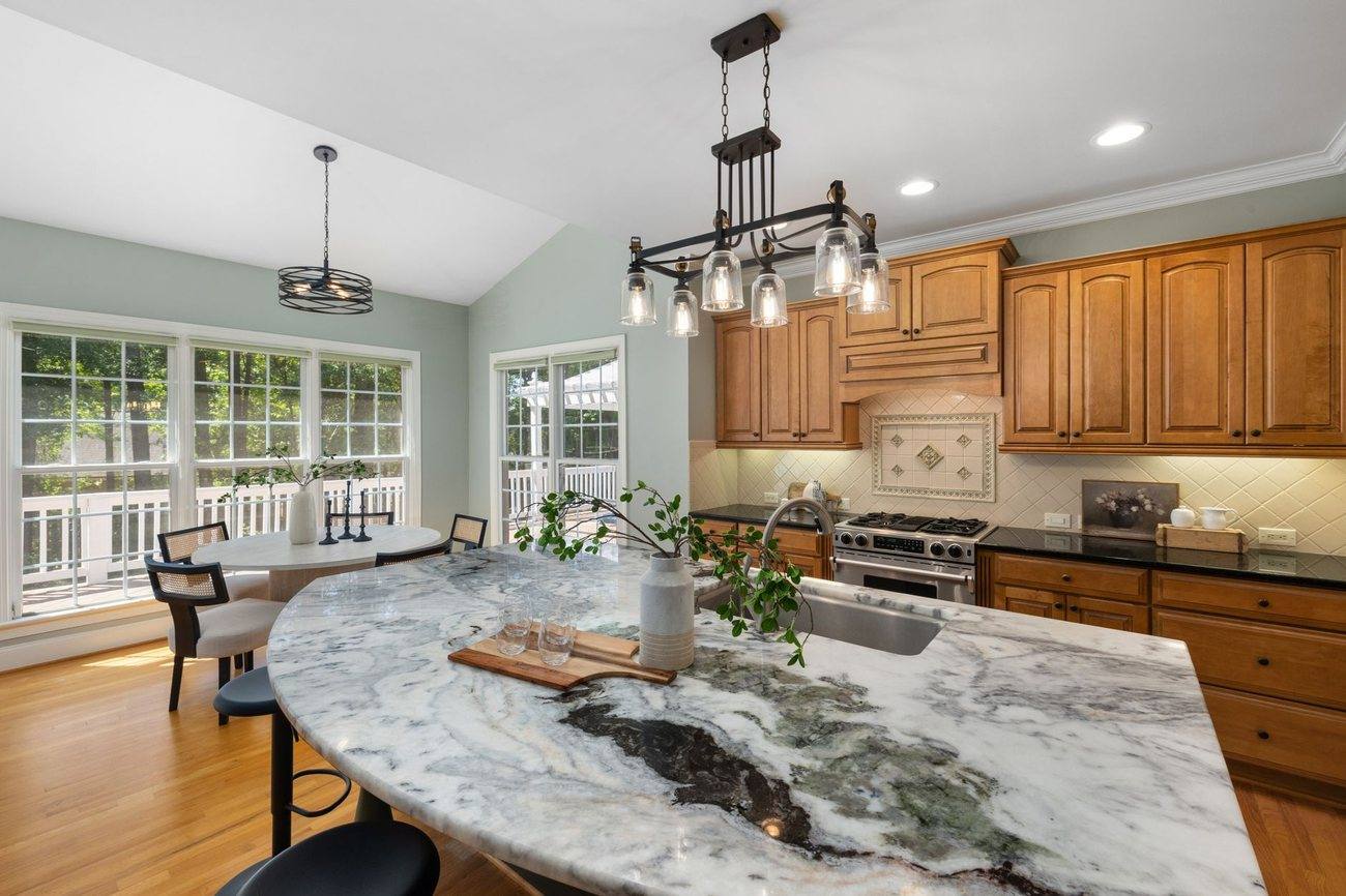 A large kitchen with a stone island and dining area beyond