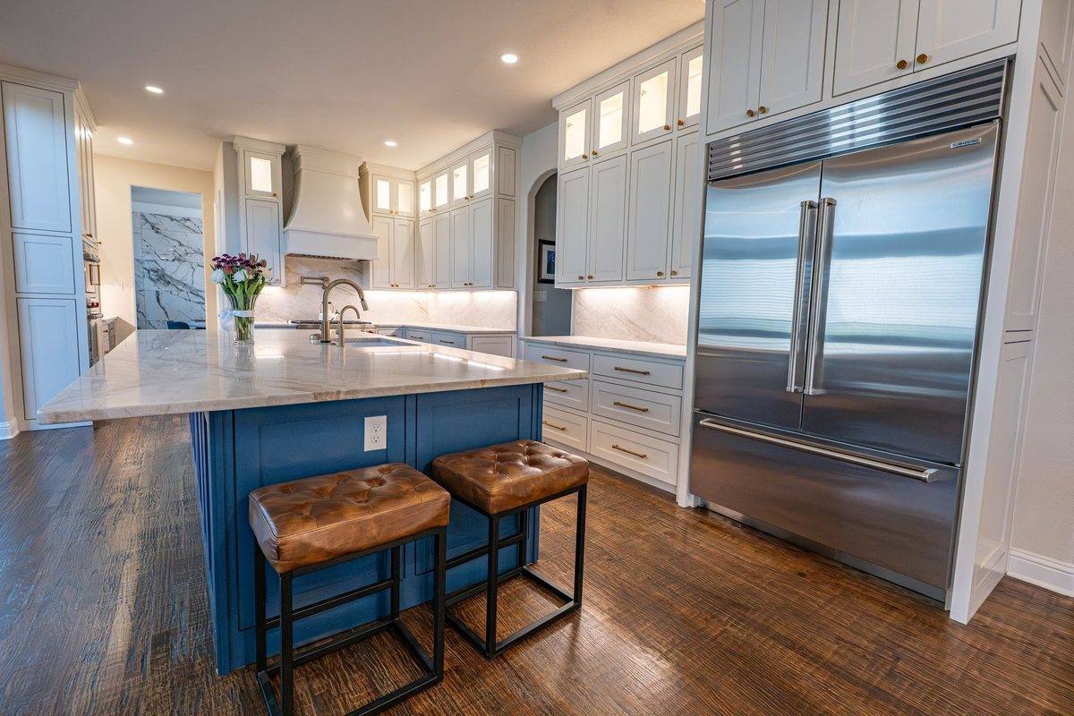 A kitchen with a deep blue island and timber stools