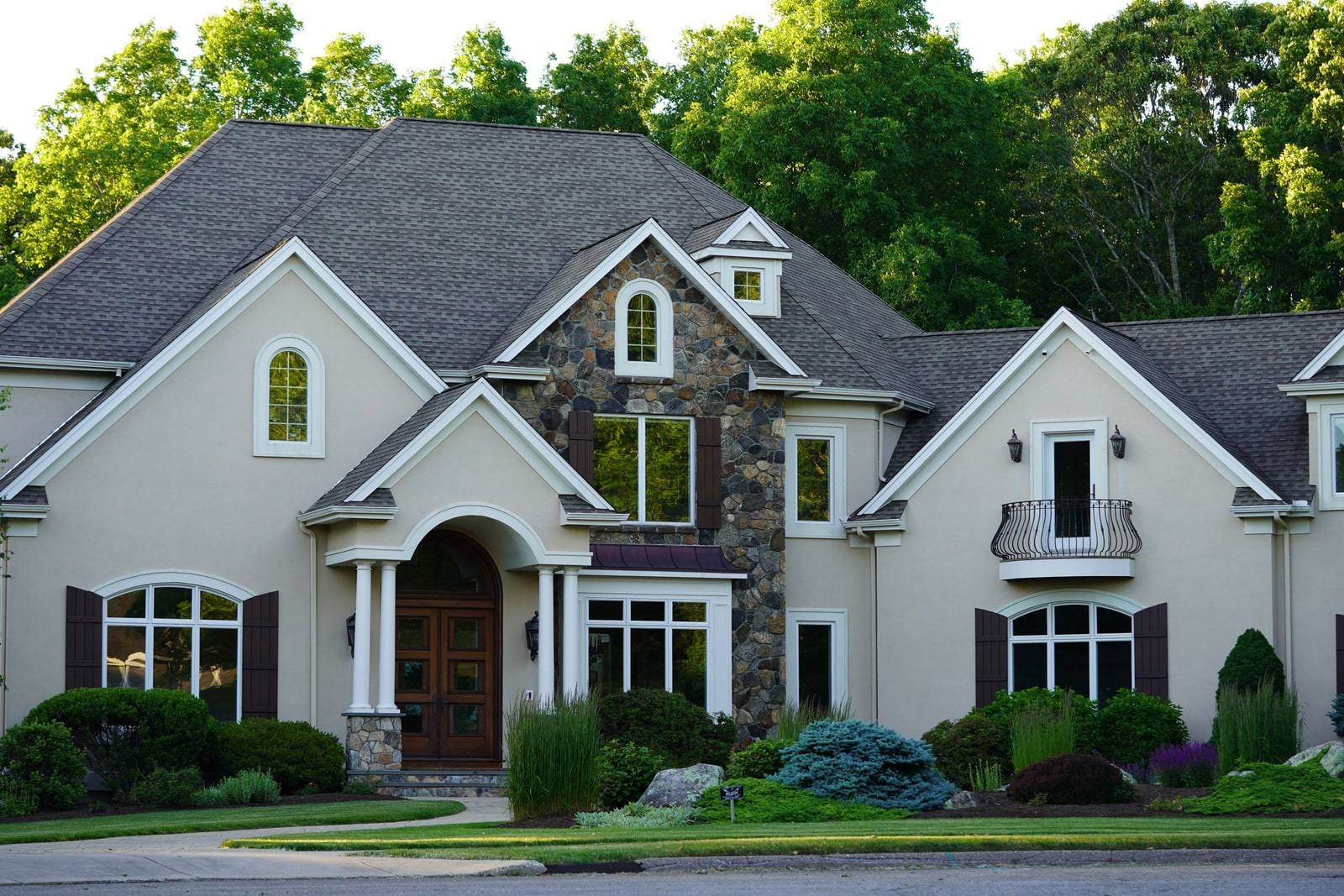 A substantial newer custom house with a stone entry, multiple gables and dormers, and a great deal of roof to flash