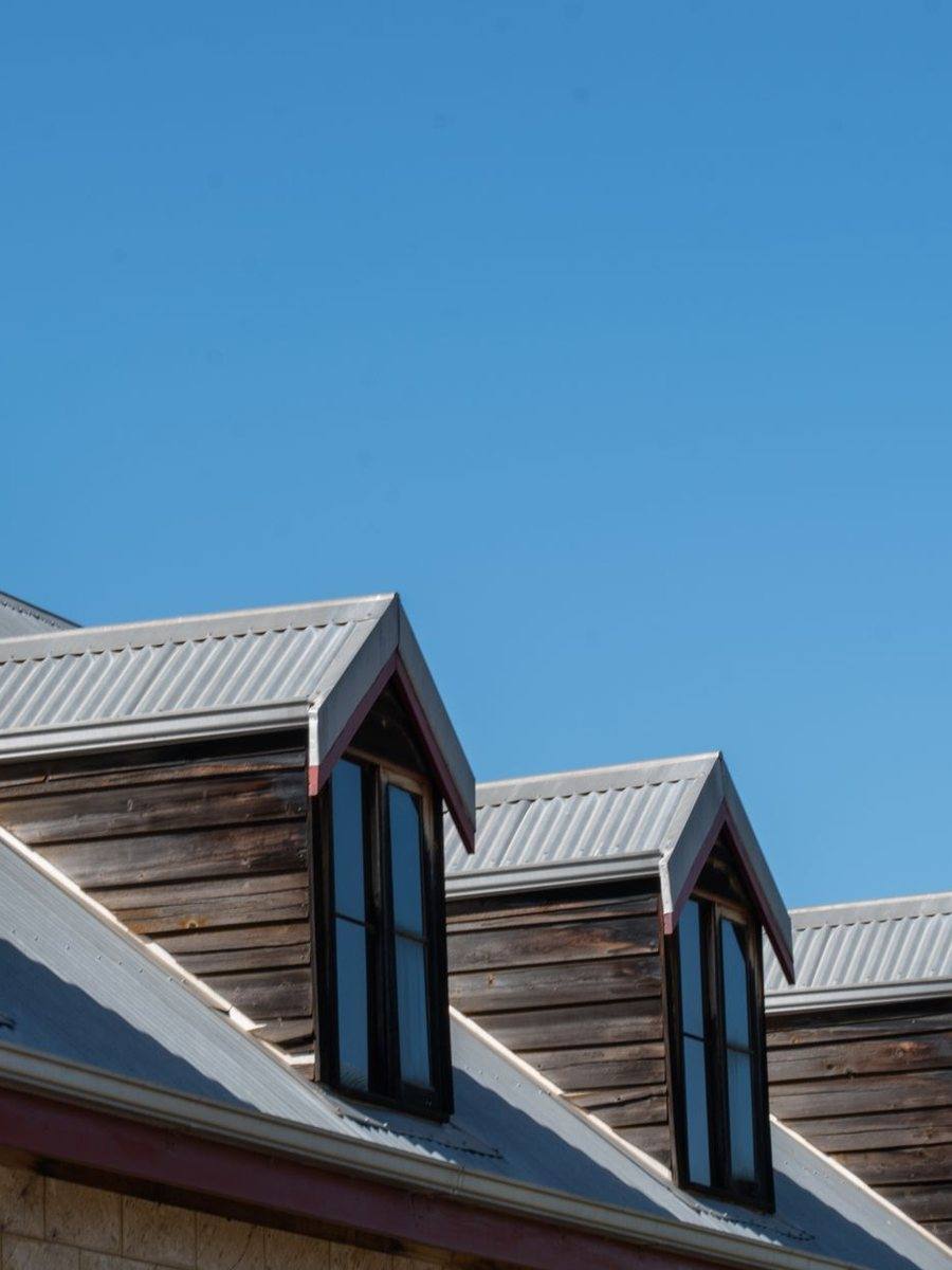 A gray standing seam metal roof with dormer windows