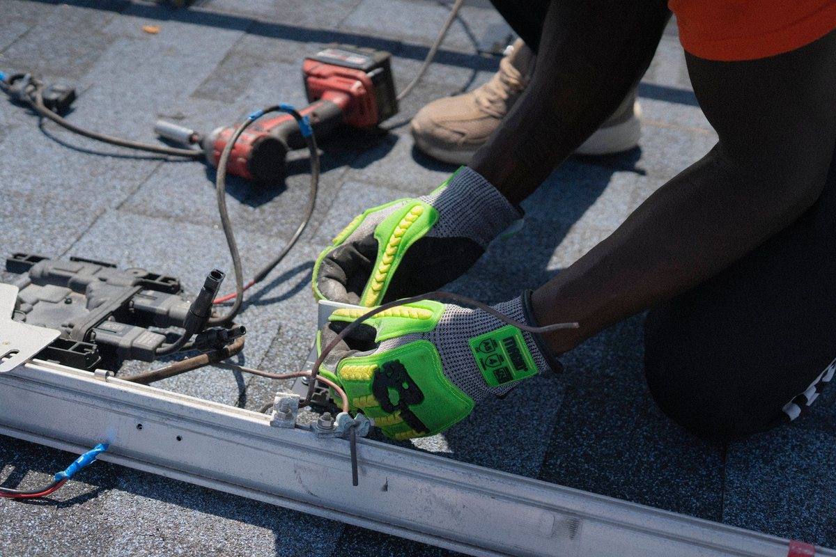 A roofer fastening shingles with a nail gun
