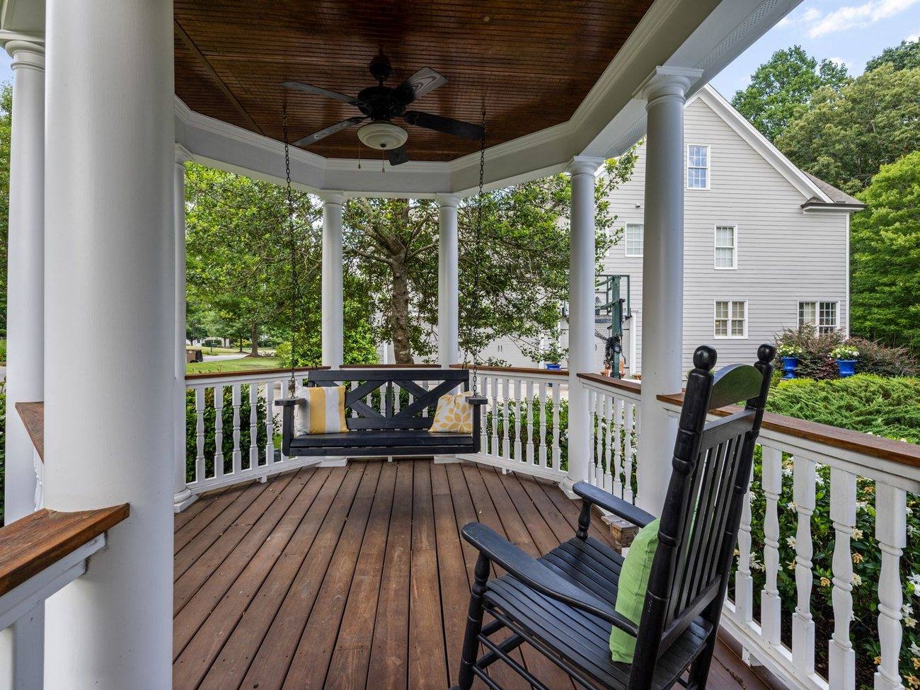 A wide covered porch with rocking chairs on a shingled house