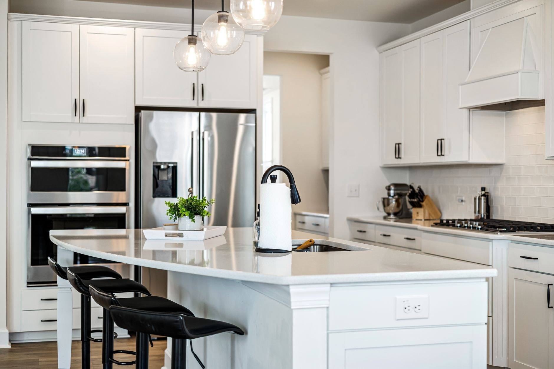 A renovated kitchen with a white island and brass pendant lights