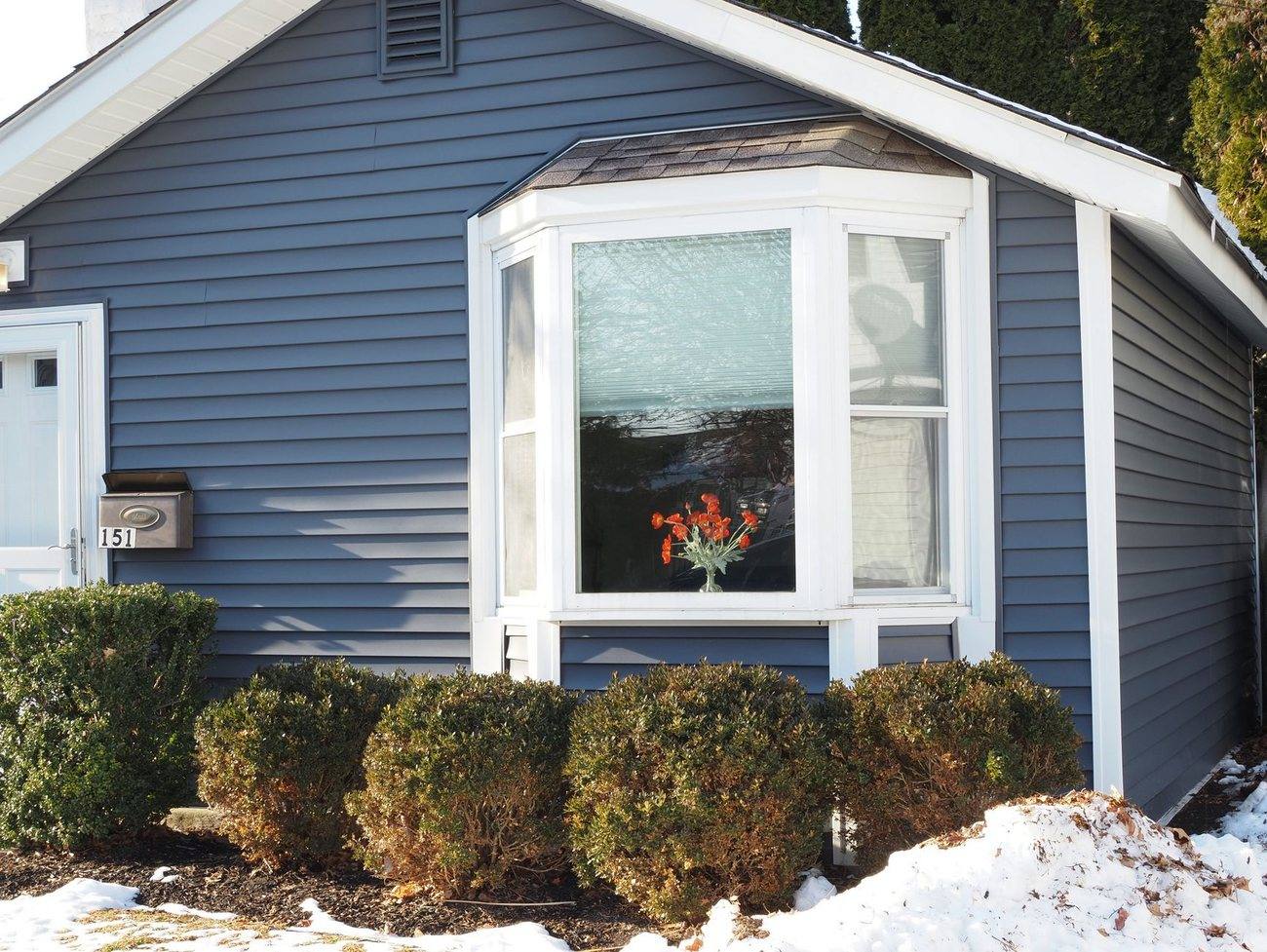 A white bay window on a blue clapboard house