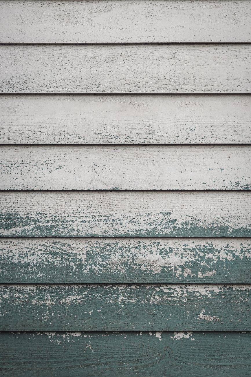 Weathered painted clapboard boards showing the paint failing