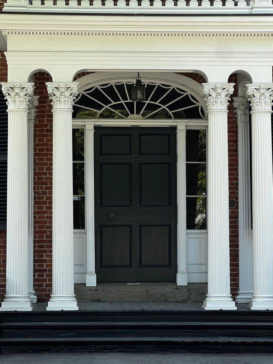 A brick colonial entrance with white columns and a fanlight