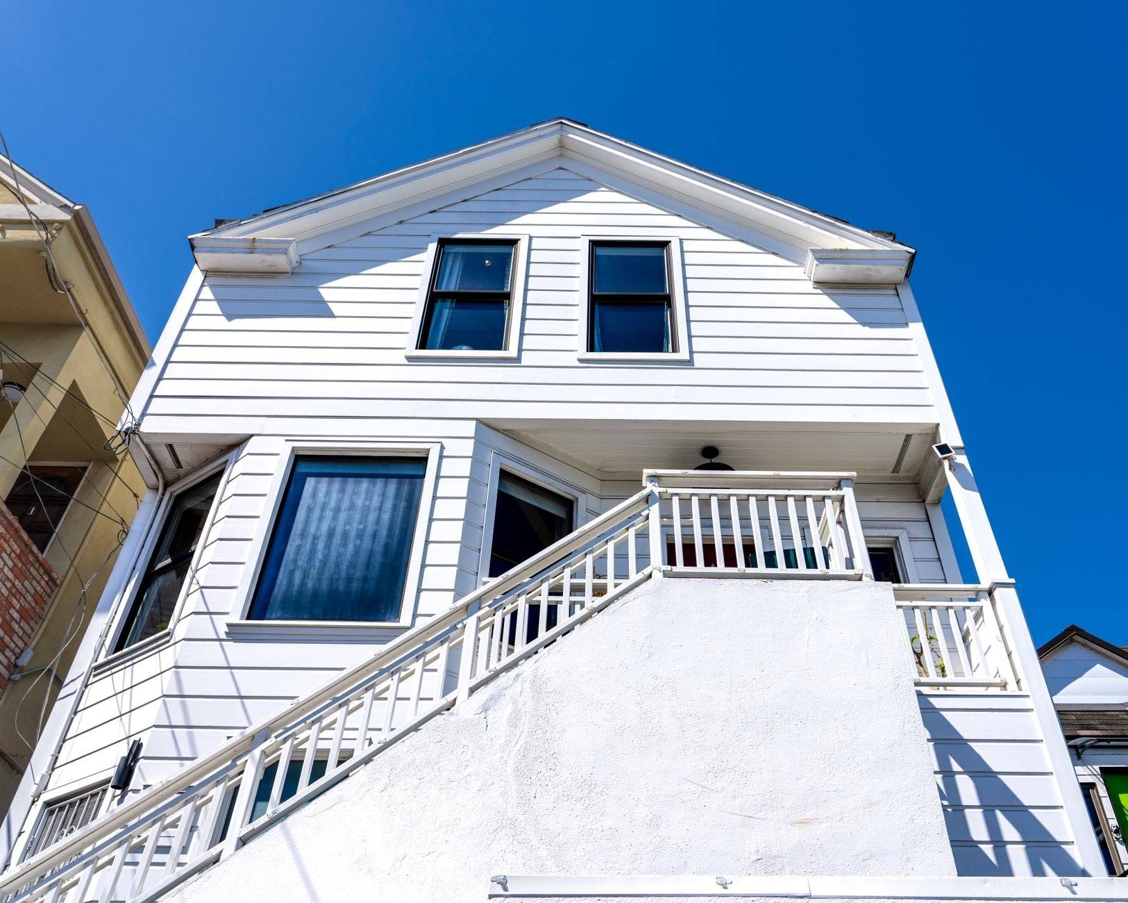 A colonial home with new white-framed double-hung windows against a clear sky