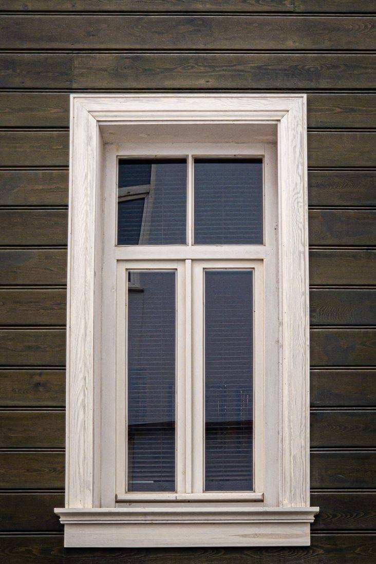A single white double-hung window in dark timber siding